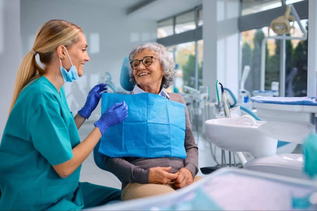 An older patient smiling with her dental hygienist.