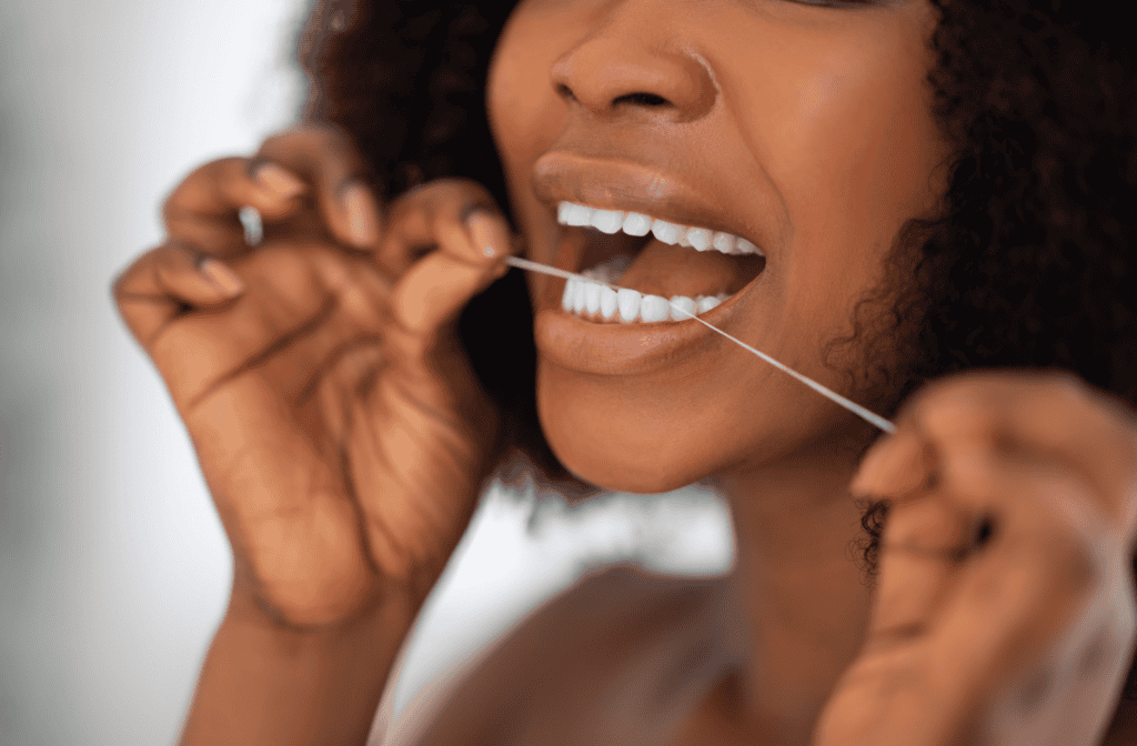 A person with stunningly white teeth flosses diligently before going to bed.