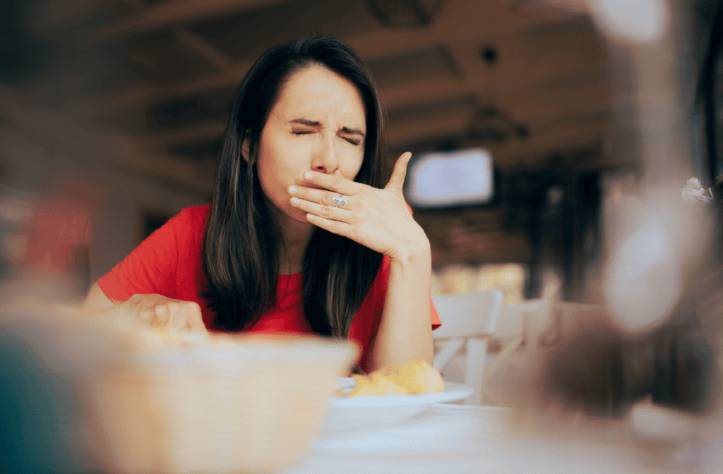 A person winces and cups their mouth during breakfast due to pain while eating.