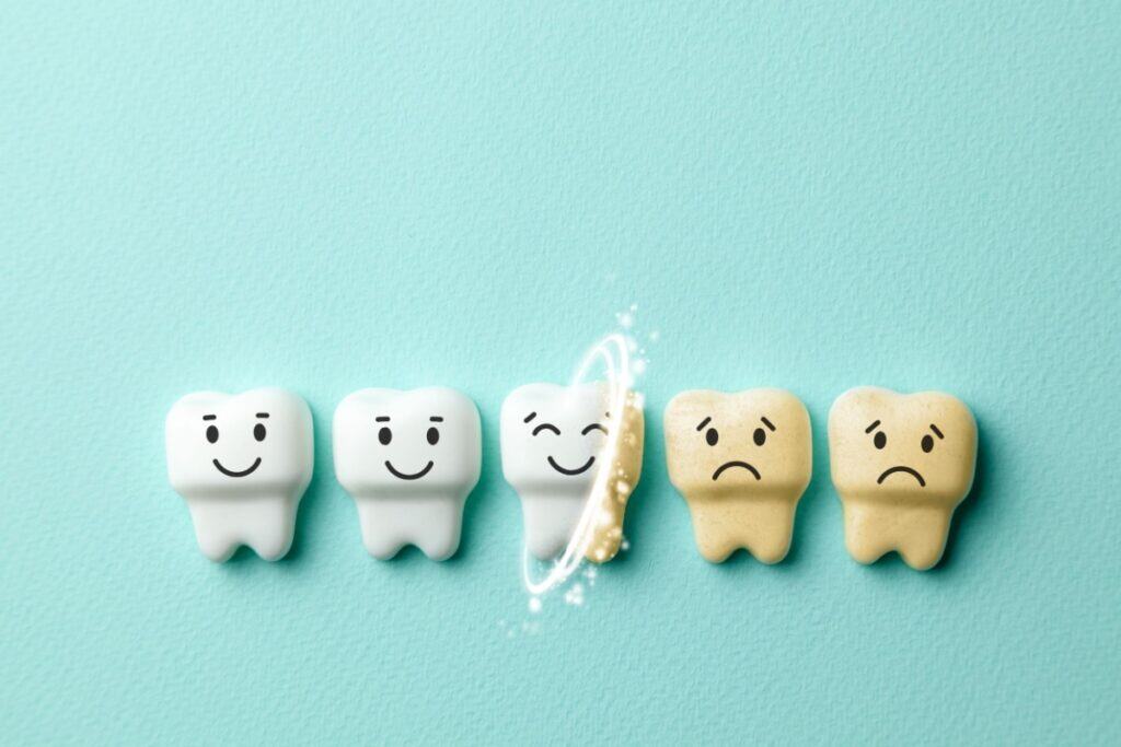 Illustrated teeth showing the contrast between clean white teeth with happy faces and stained yellow teeth with sad faces, indicating the importance of regular brushing.